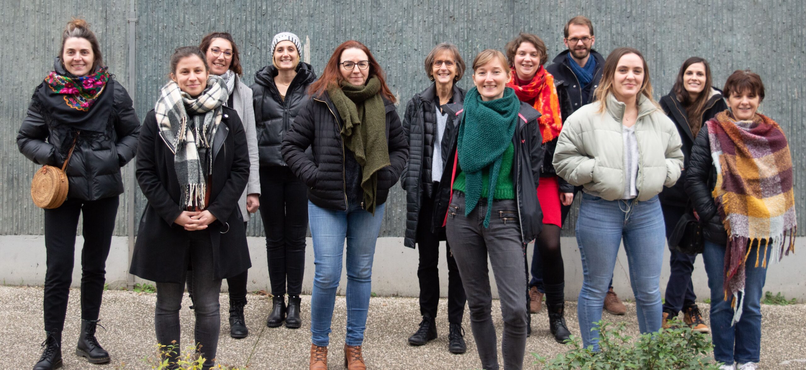 Groupe de personnes face caméra devant un mur, les mains dans les poches