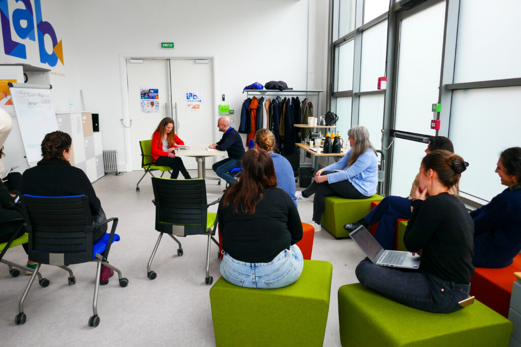 Photo d'une session de travail collectif du prix 2D avec des personnes assises en cercle sur des blocs verts