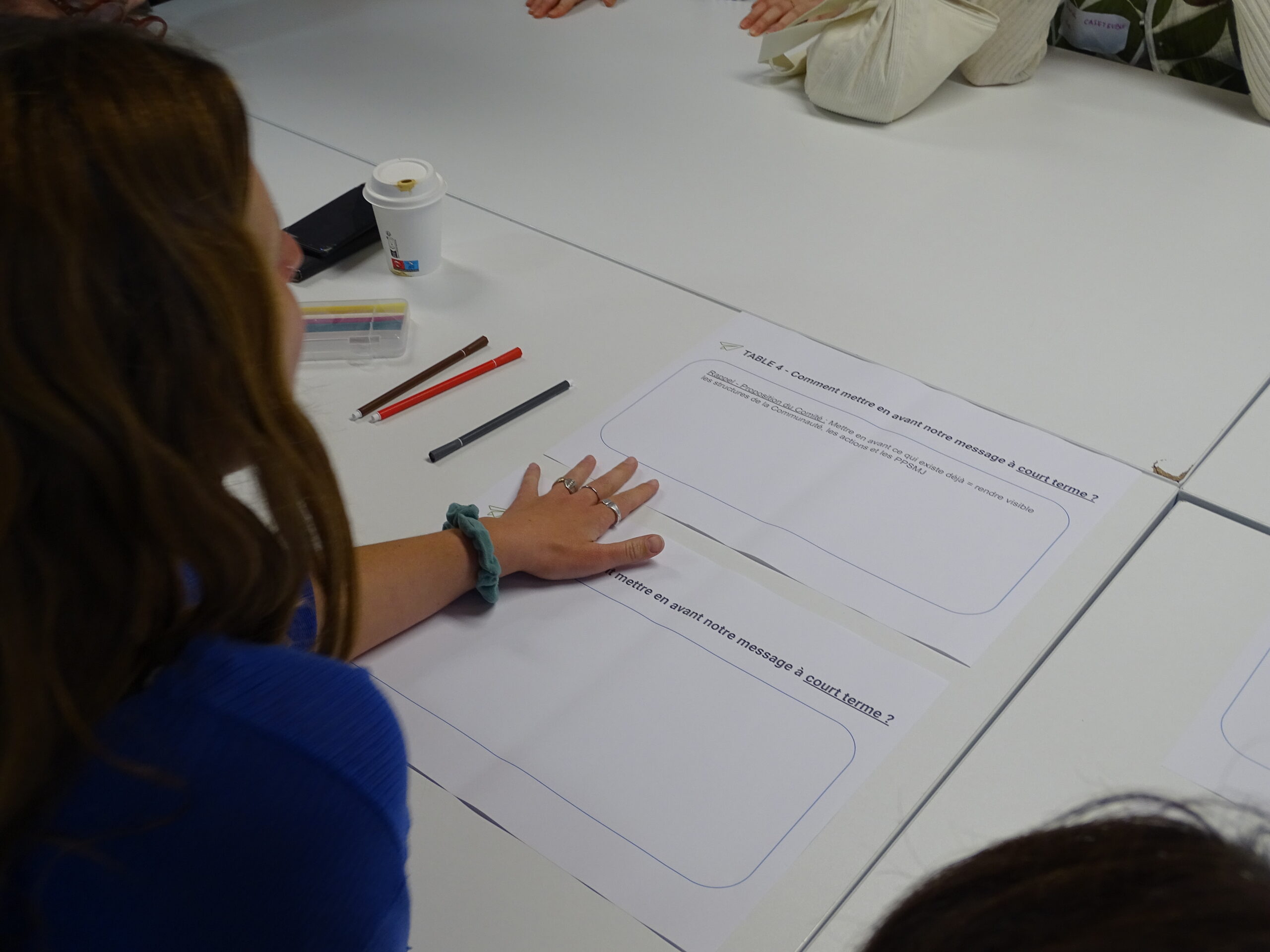 Atelier de travail, plusieurs personnes autour d'une table sur laquelle est posée une feuille qui est en train d'être remplie par le groupe